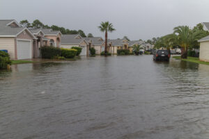 a flooded street with houses and cars / Most Hidden Danger: Mold Risks in Florida Homes During Hurricane Season / Mold Risks in Florida Homes: A Silent Menace / The Impact of Mold Risks on Health / How Hurricanes Season Exacerbate Mold Risks in Florida Homes / Effective Mold Management During Hurricane Season / ETA Mold Testing and Inspection in Florida
