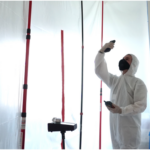 Professional mold inspection for eta in protective suit inspecting wall for mold growth and moisture.