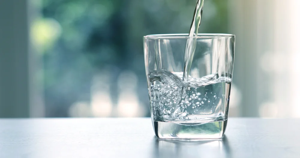 a glass of water being poured into a glass / Top Benefits of Using a Water Purifier - Why Clean Water Matters - Benefits of Using a Water Purifier - Types of Water Purifiers and Their Features - ETA Mold Inpection in Florida