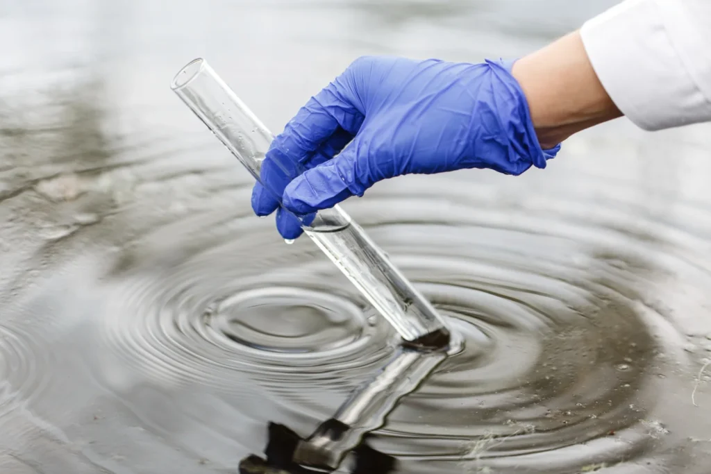 a hand in blue gloves holding a test tube in water / The Importance of Testing Your Drinking Water in Florida / Why Testing Drinking Water Matters / Common Water Quality Issues in Florida / What Drinking Water Tests Look For / How Often Should You Test Your Water? / The Benefits of Professional Testing / Safe Water Supports Your Family and Your Home / Trust ETA for Safe Drinking Water Testing in Florida / ETA Mold Testing in Florida