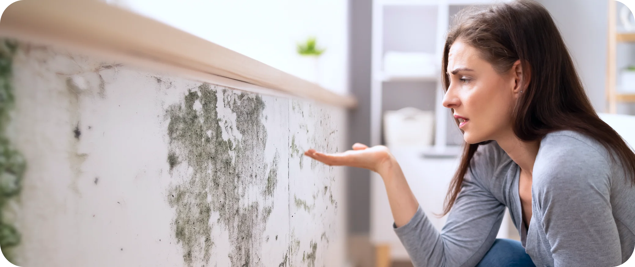Woman looking worried at toxic mold damage on a home wall construction