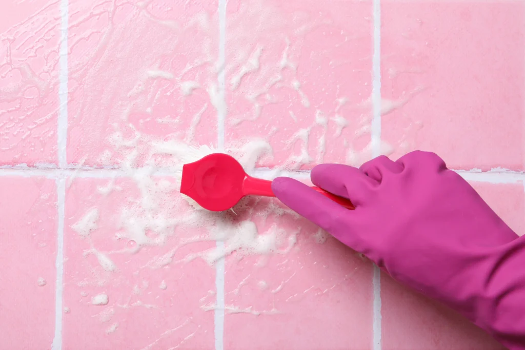 Washing Pink Tiles in Rubber Gloves Close up - How to Remove Mold From Shower Grout - Environmental Testing Agency