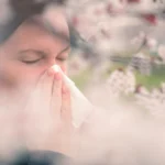 woman sneezing in front of blooming cherry tree - Can Mold Make You Sick?
