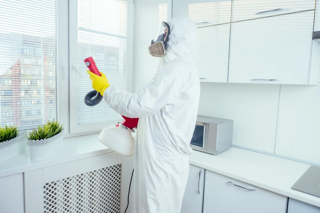 Does Ozone Kill Mold? A Complete Guide 1 Professional mold inspection in a protective suit spraying disinfectant to clean mold in a bathroom.
